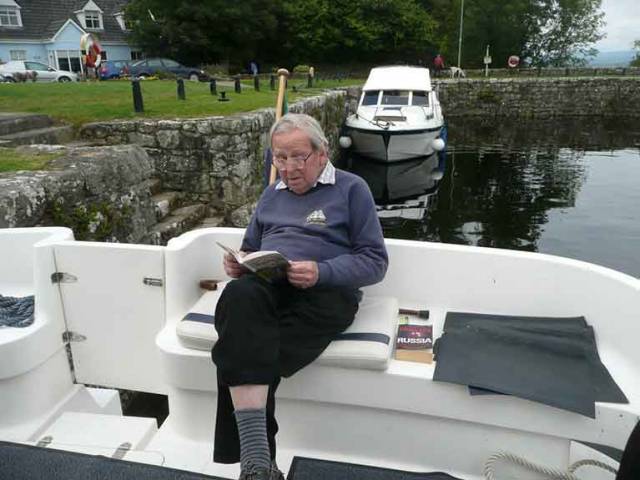 Always interested. Michael Booth, aged 92, aboard the family’s cruiser in Garrykennedy on Lough Derg in 2011, absorbed in one book with another – about Russia – ready to hand