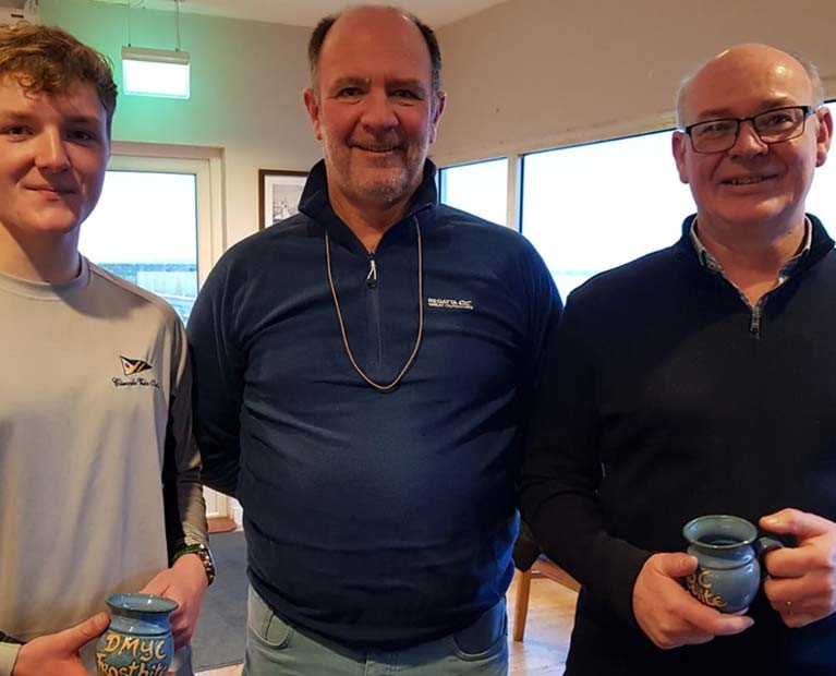 Peter &amp; Stephen Boyle (GP14) pick up their Frostbite Mug from Race Officer Cormac Bradley (centre)