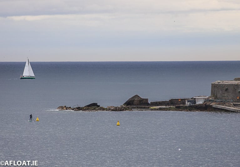 A yacht makes its way past Sandycove on Dublin Bay watched by a Stand Up Paddleboarder at the Forty Foot