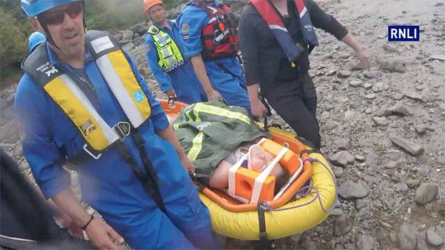 Coastguard rescue team members stretcher the injured cyclist to the lifeboat