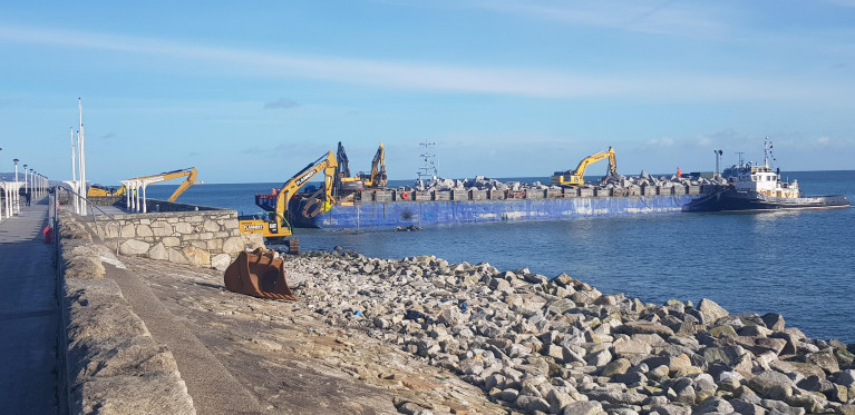 East Pier, Dun Laoghaire Harbour where contractors using heavy machinery on board a barge with tug Vanguard on station just offshore in Scotsman's Bay last month. Since then granite rocks continue to be placed in position shoring up previous damage caused by Storm Emma in 2018. 