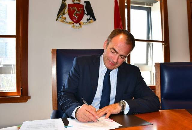 Manx Treasury Minister Alfred Cannan signs the formal agreement to control the sea services shifted to the island's government.