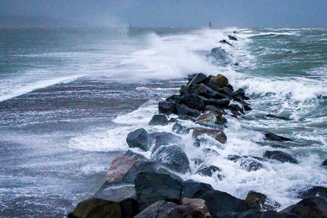 Waves break over the Great South Wall at Poolbeg, Dublin