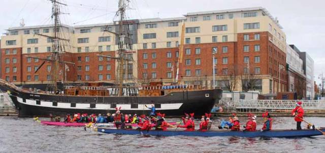 Dragon boats racing with the back drop of the Tall Ship Jeanie Johnston on the River Liffey