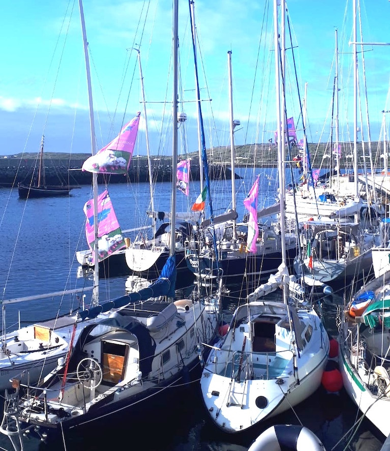 Summer evening sunshine greets the Galway Bay Sailing Club fleet as they welcome home the Transatlantic-voyaging ketch Danu (at centre) at Kilronan in the Aran Islands at the end of July 2020