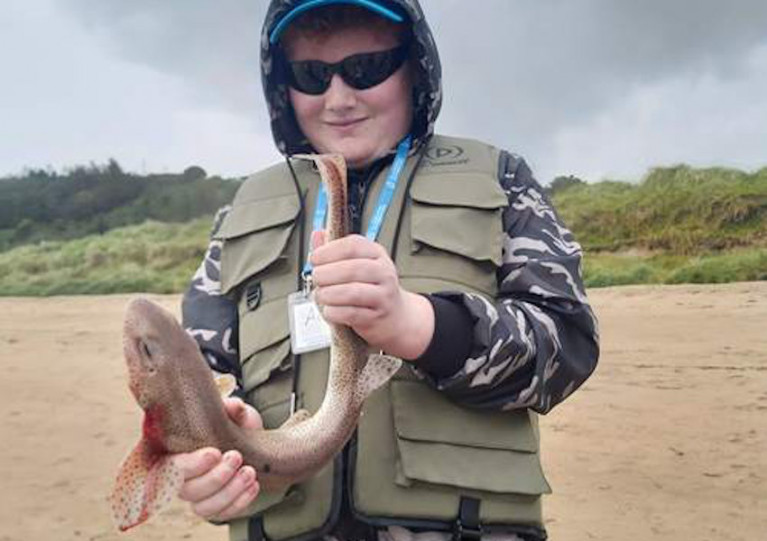 One of the young anglers in the Donegal Foróige group with a dogfish caught on their visit to Buncrana beach in August
