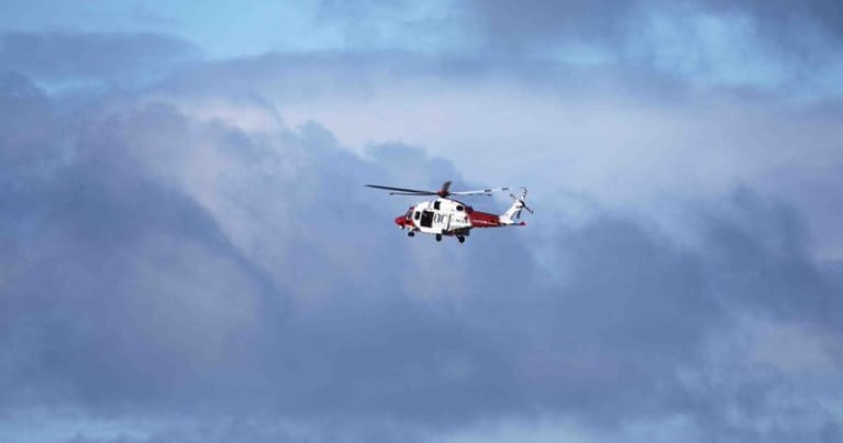 The body of a man was found on the shore near Ynys Y Fydlyn in Anglesey on Wednesday. Above a UK Coastguard helicopter involved in the search off north Wales.