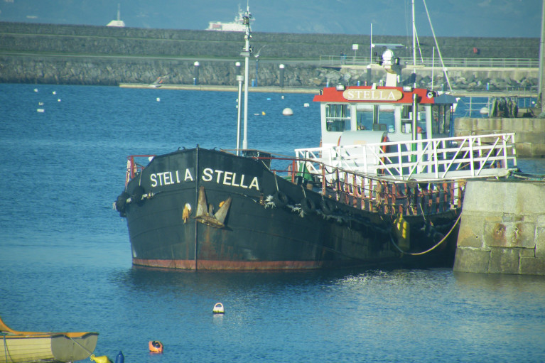 Stella a former Dutch canal-cargo barge in this file photo when initially the vessel was berthed at the pierhead of the Old Pier (dating to 1767) which as the name suggests is Dun Laoghaire Harbour&#039;s oldest. The barge subsequently was relocated to the adjacent Coal Harbour. Take a closer look above the West Pier were the funnel and upper superstructure of a Seatruck Ferries &#039;P&#039; class ro-ro freighter is seen underway having departed neighbouring Dublin Port and when bound to Britain, either Heysham or Liverpool. 