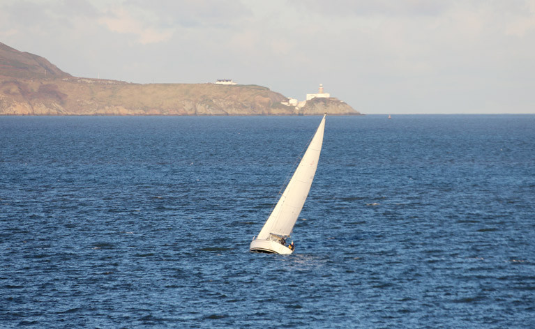 New year sail - A solitary sailing cruiser enjoys a New Year&#039;s Day sail on Dublin Bay with Howth&#039;s Baily lighthouse in the background