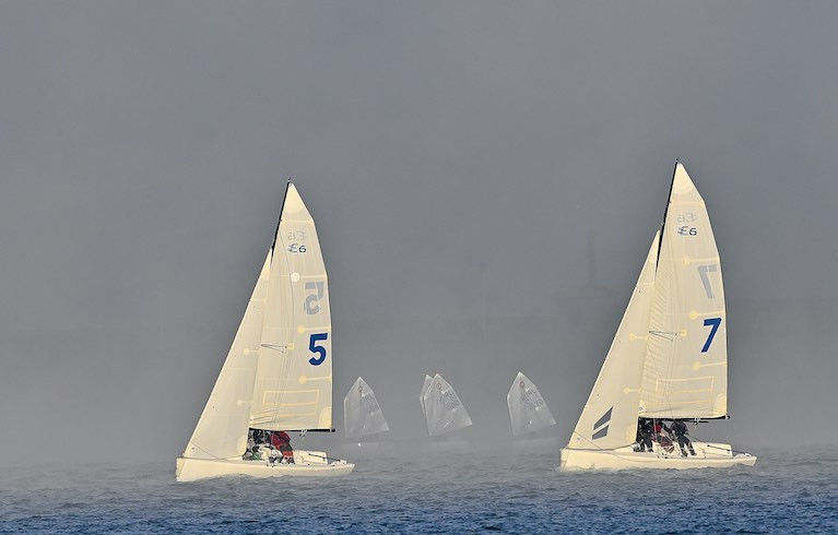 Two Elliott Six Metre keelboat in the foreground and Optimist dinghies sailing in the mist at Dun Laoghaire Harbour 