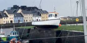 Galway Bay SC sailor Aaron O’Reilly sent us this brief video of the clinker-built fishing boat which ended up perilously balanced – but miraculously secured – right on top of the pier across the Corrib from the Claddagh