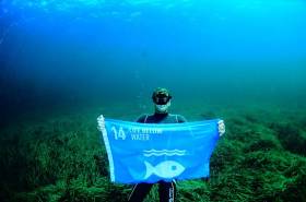 Free diving world champion Umberto Pelizzari raises a flag below water to highlight the plight of life below water