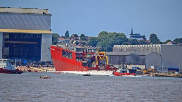 The hull of newbuild RRS Sir David Attenborough pushed a big wave out into the Mersey from the shipyard of Cammell Laird, Birkenhead. A yellow submarine named Boaty McBoatface forms part of the ship's sophisticated equipment. 